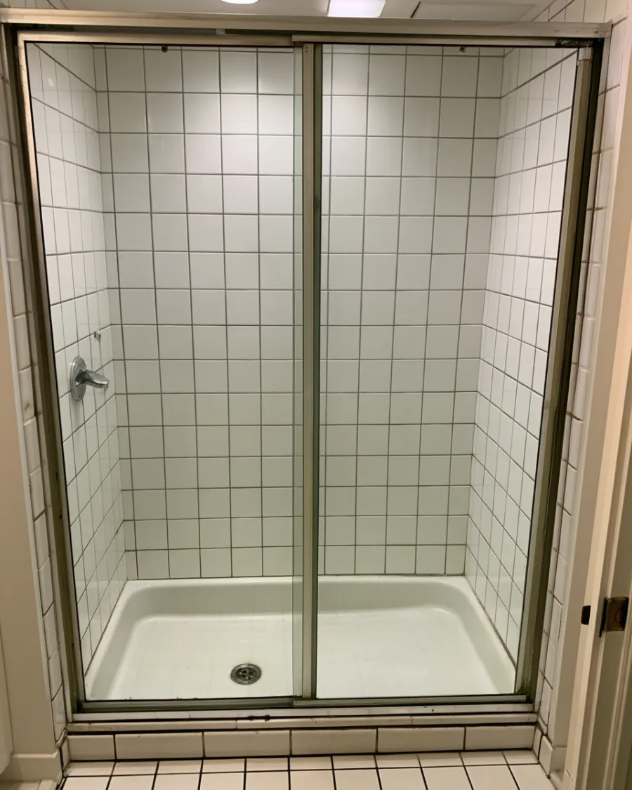 The same shower after a deep clean, white grout and clear glass
