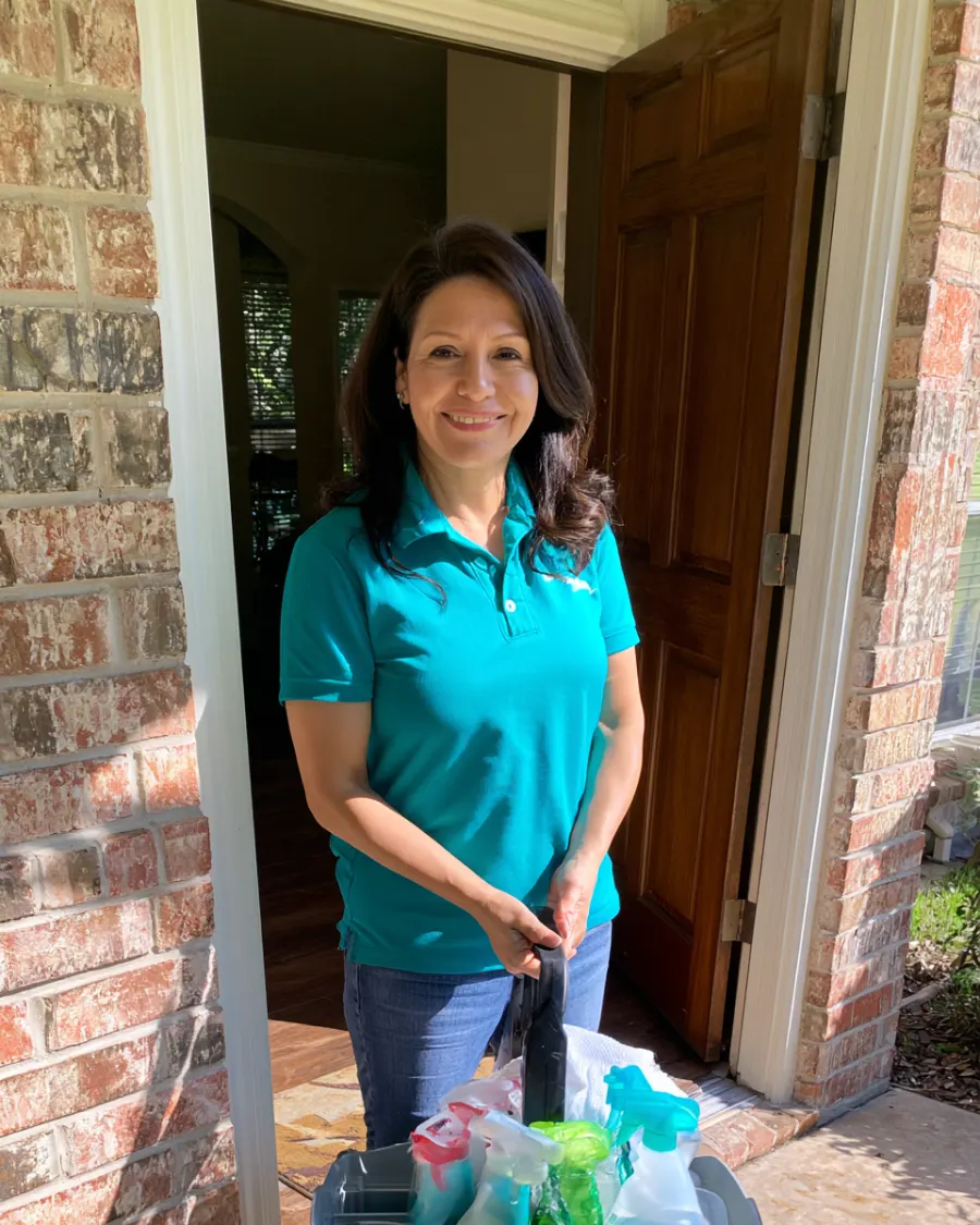 Rosa, the owner, at a client's front door with her cleaning caddy