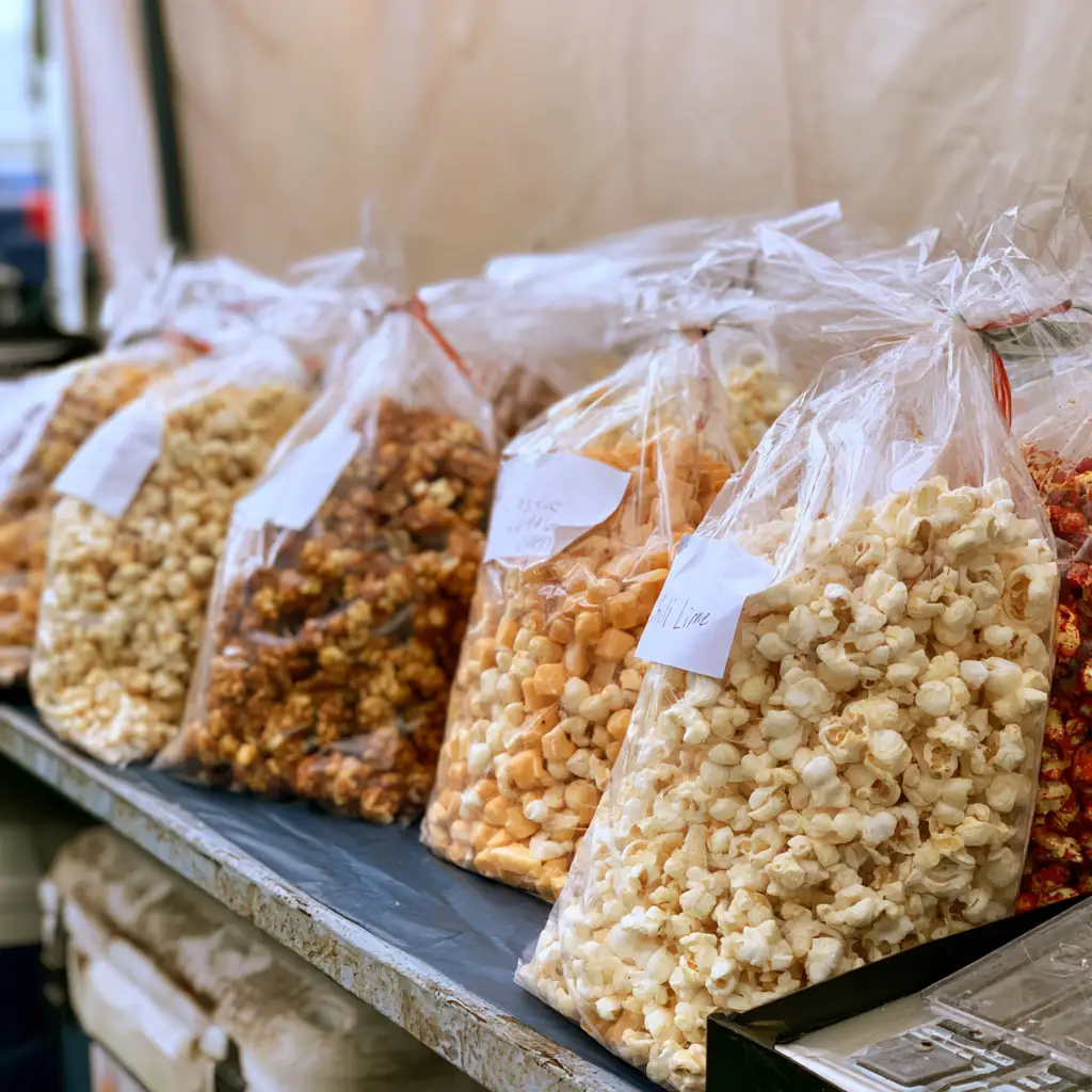 Labeled bags of kettle corn, caramel and cheddar popcorn lined up on the table