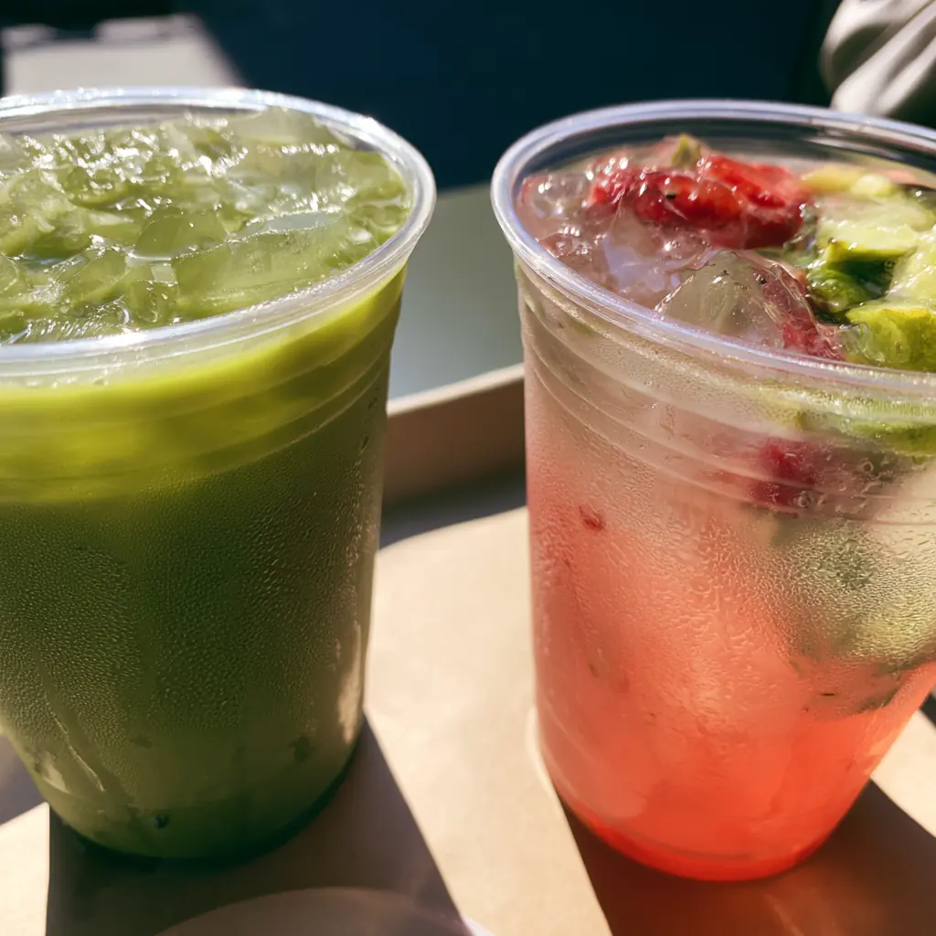 An iced matcha latte beside a pineapple refresher
