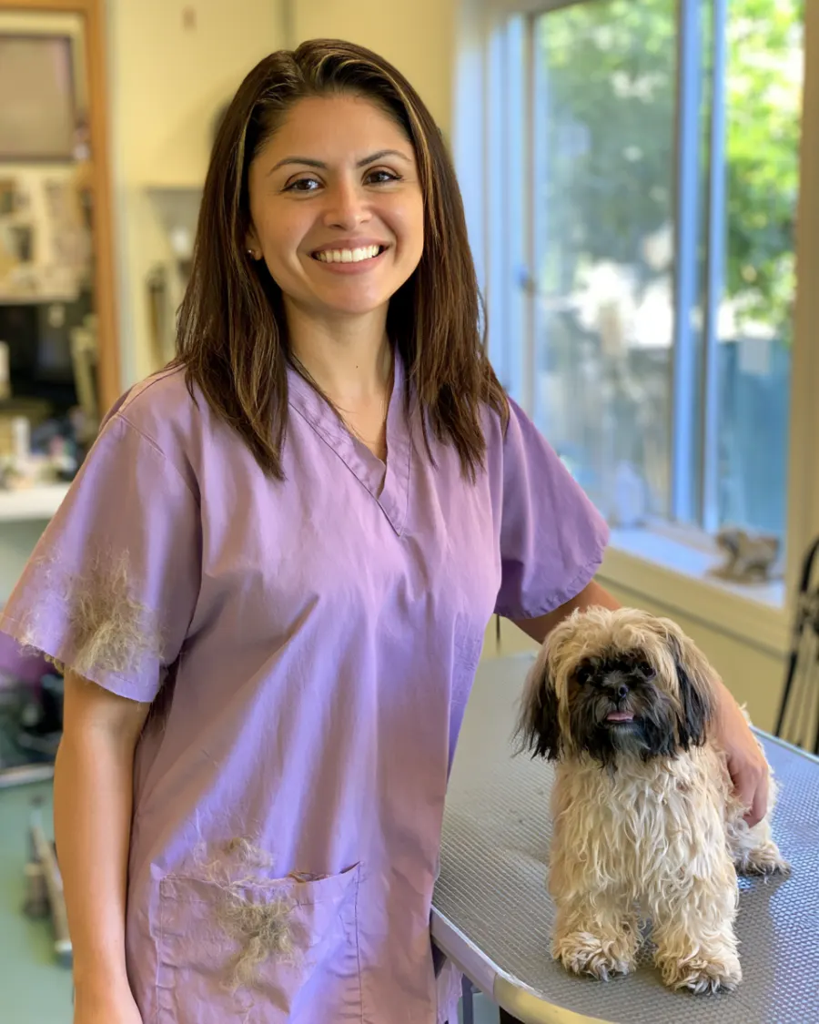 Marisol, the owner, smiling next to a small dog on the grooming table